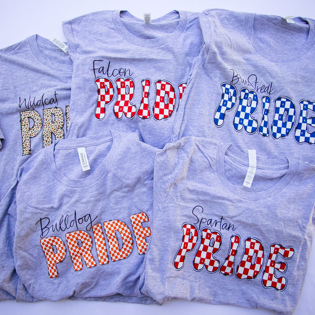 Five heather gray t-shirts with different collegiate-style 'Pride' graphics in red, white, blue, orange, and leopard print, arranged in a flat-lay collage.