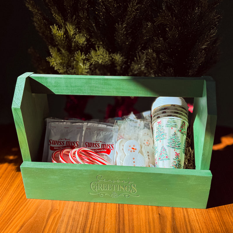 Green wooden box with Christmas-themed items on a wooden surface