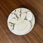A round wooden ornament or decorative piece with laser-cut reindeer features, including antlers, a nose, and hooves, displayed on a wooden tabletop.