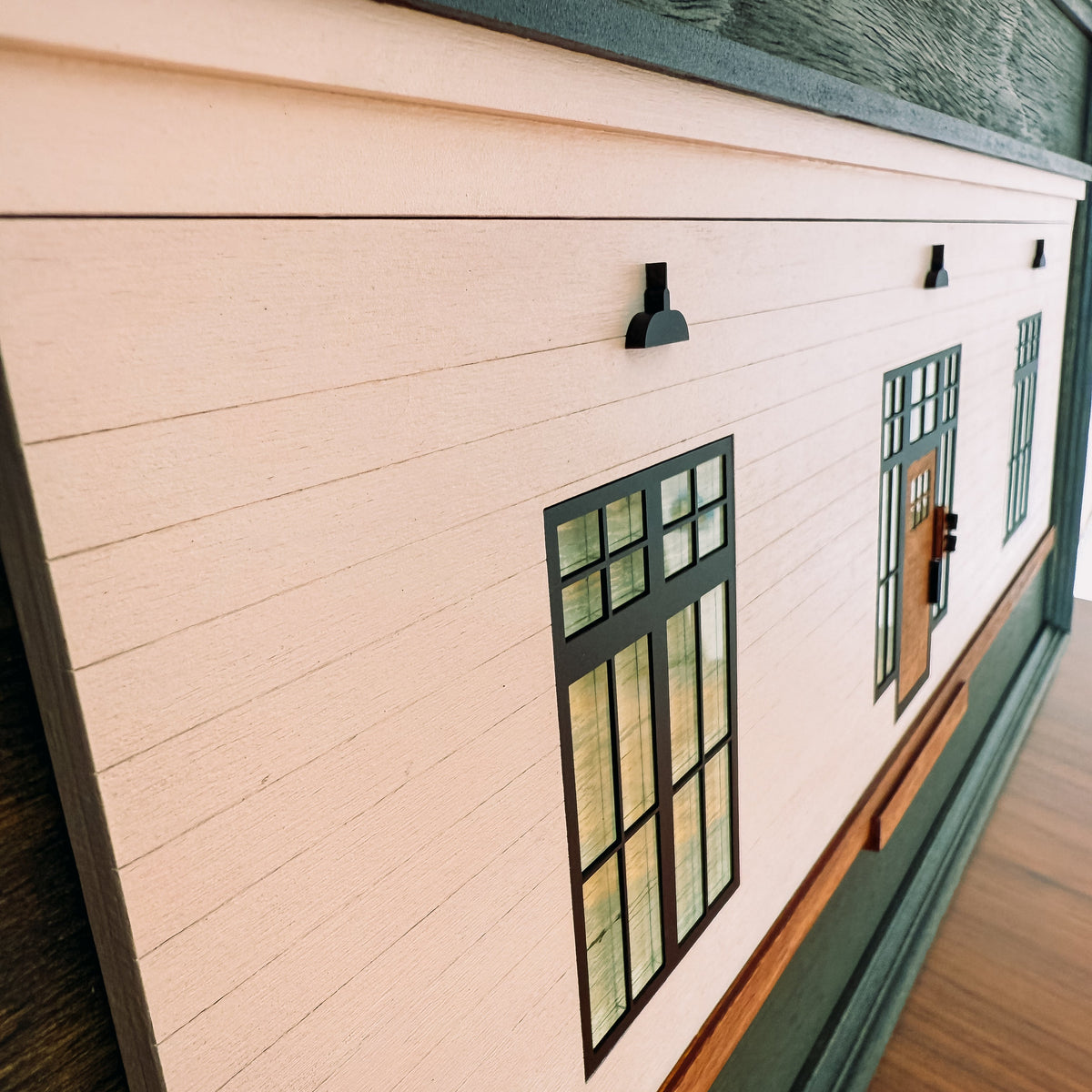 Close-up of a wooden cabin art with a window design on a wooden table.