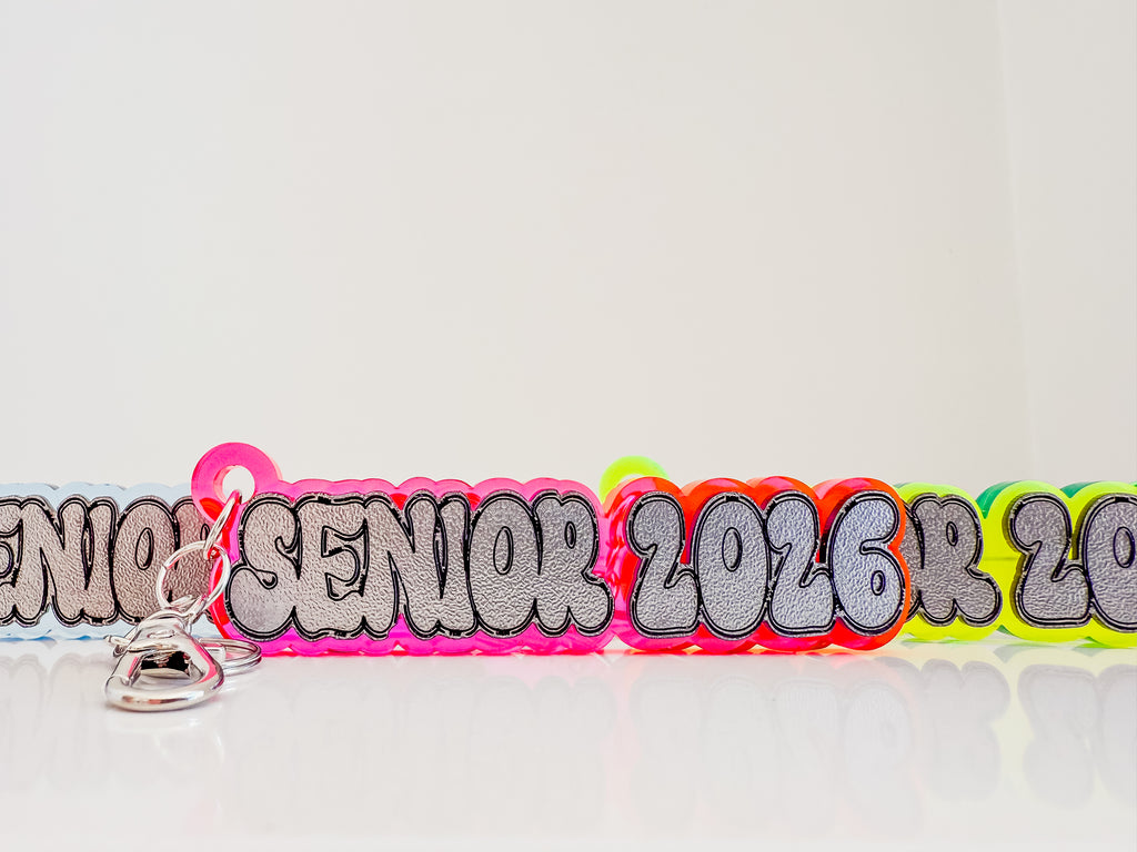 Neon-colored 'Senior 2026' lanyard with a keychain on a white background by October House Co. in Hartville, Ohio.