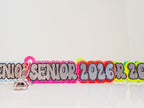 Neon-colored 'Senior 2026' lanyard with a keychain on a white background by October House Co. in Hartville, Ohio.
