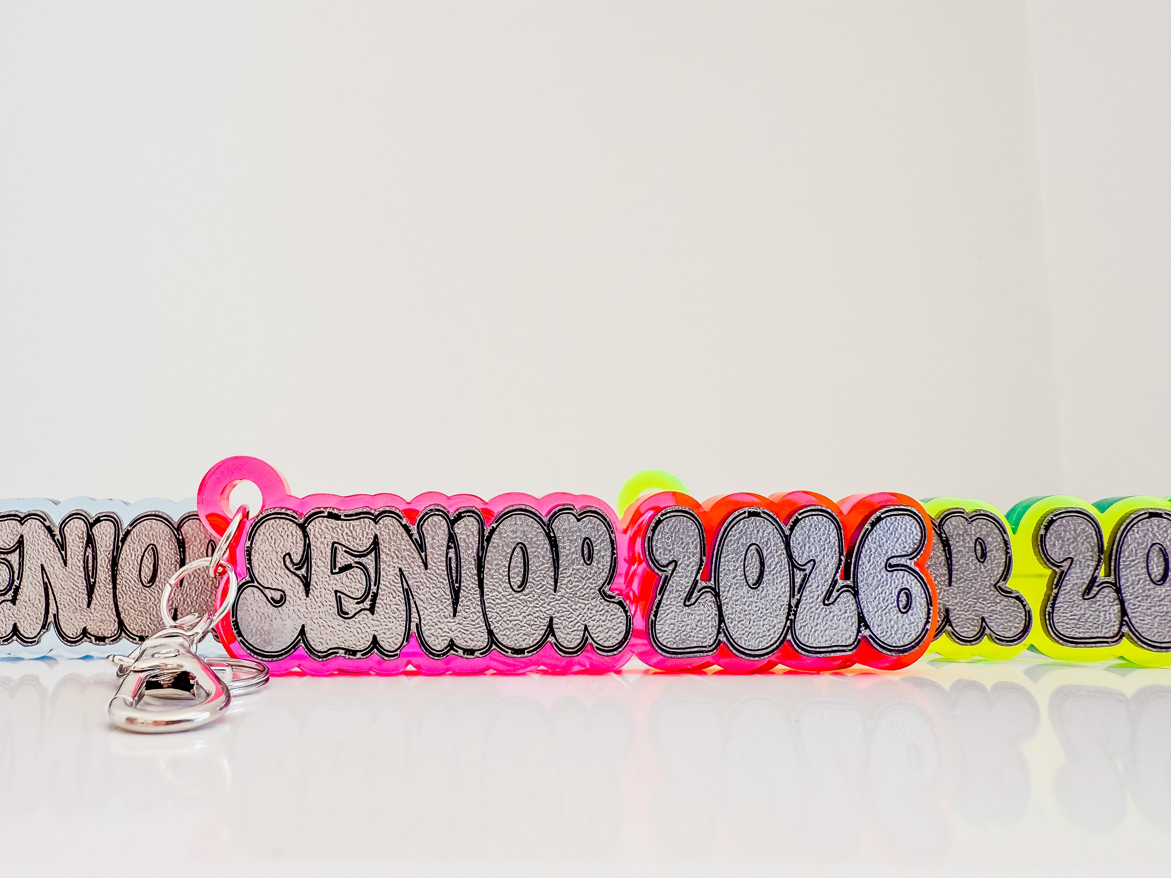 Neon-colored 'Senior 2026' lanyard with a keychain on a white background by October House Co. in Hartville, Ohio.
