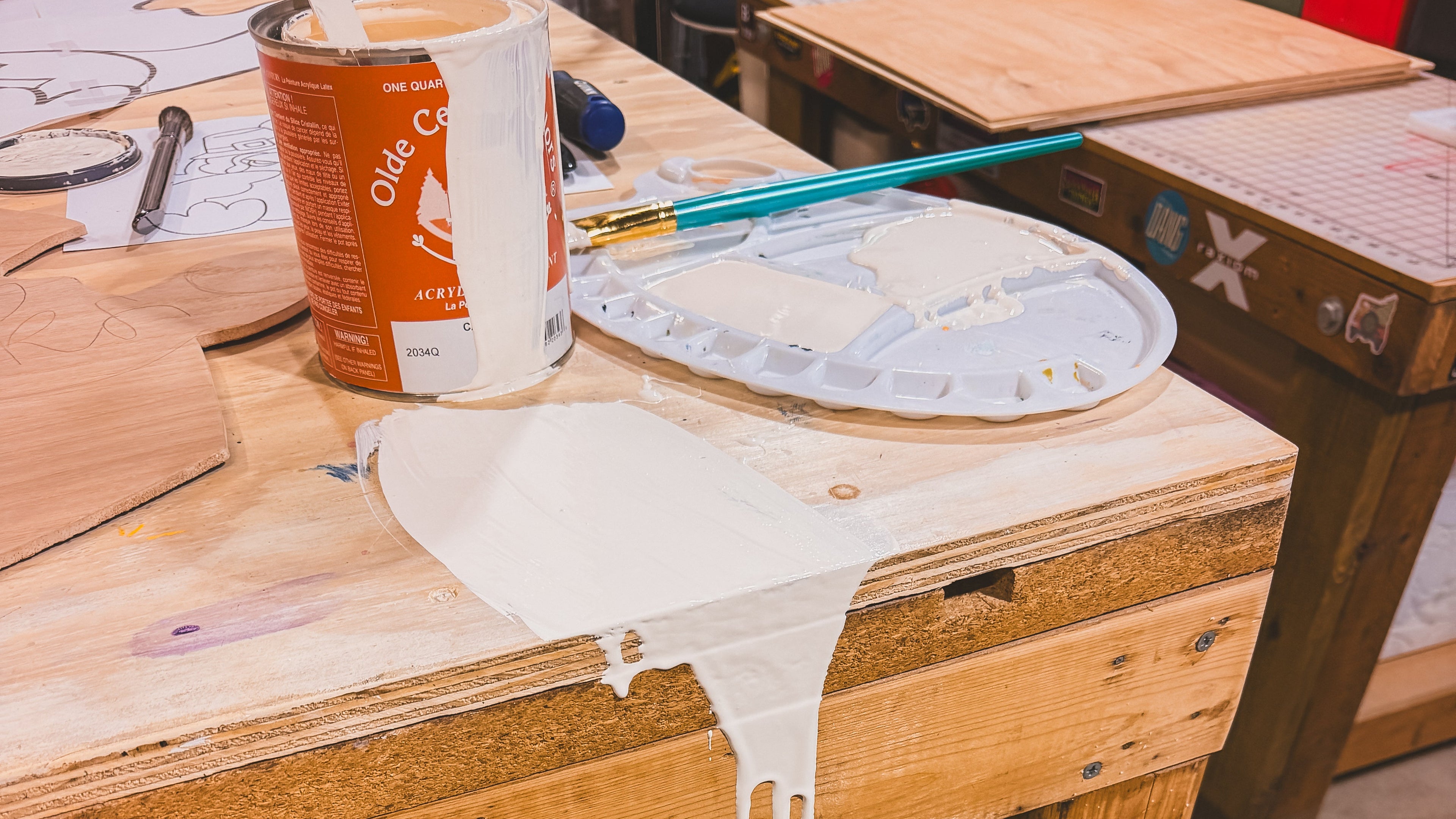 October House Co.'s wooden workbench with paint supplies including a can of paint, brushes, and a palette in Hartville, Ohio. 