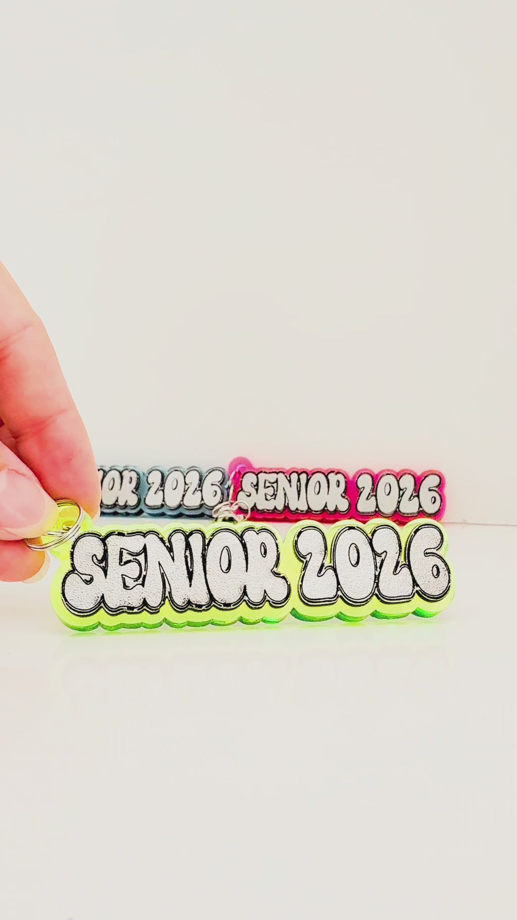 Video showing neon acrylic "senior 2026" keychains